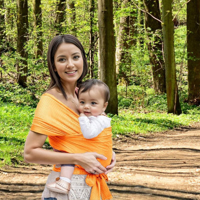 Maman forêt portant bébé dans écharpe de portage bébé orange douce ergonomique