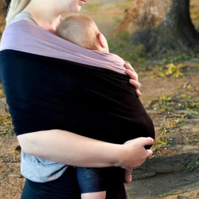 Maman-en-forêt-tenant-dans-ses-bras-son-bébé-installé-rapidement-dans-son-écharpe-de-portage-ergonomique.