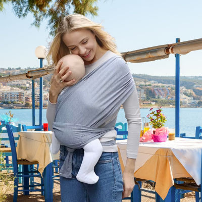 Maman restaurant bord mer portant bébé dans écharpe de portage legère facile à installer