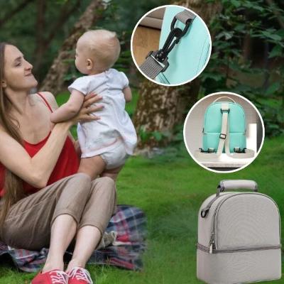 maman-joue-avec-son-bébé-qui-se-trouve-à-côté-de-son-sac-à-langer-gris-avec-des-sangles-pour-l-accrocher-dans-le-dos-et-ajustable-grâce-aux-clips