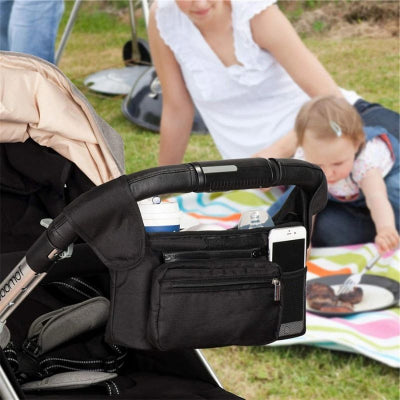 Maman-en-pique-nique-avec-sa-fille-à-côté-de-laquelle-se-trouve-la-poussette-sur-laquelle-est-accroché-le-sac-à-langer-spécial-poussette-à-sacoche-lingettes-détachable-dans-un-parc