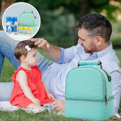 papa-caresse-les-cheveux-de-son-bébé-habillée-d-une-robe-rouge-assise-à-côté-de-son-sac-à-langer-vert-contenant-3-mini-biberons-et-un-grand-dans-un-parc-arboré
