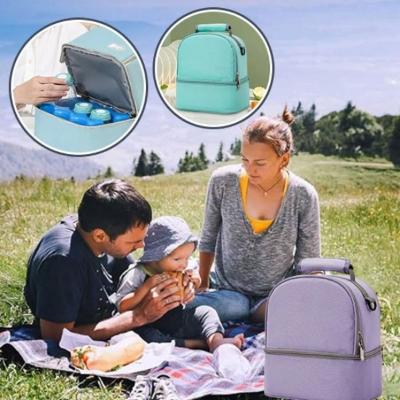 bébé-mange-une-crêpe-entre-ses-parents-assis-à-côté-de-son-sac-à-langer-violet-ouvert-laissant-apercevoir-les-protections-des-biberons-sur-une-couverture-multicolore-dans-un-pré-en-montagne