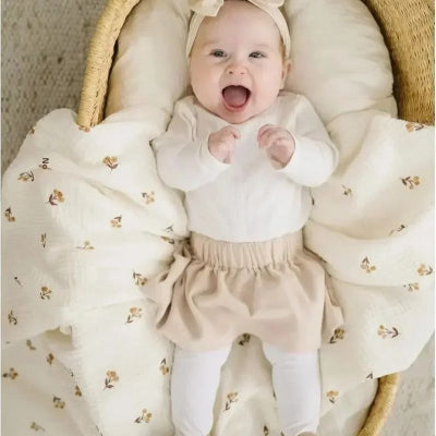 Bébé souriant allongé sur couverture bébé légère coton motif dans landau 