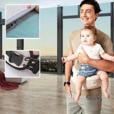 Bébé porté dans porte-bébé papa beige face au monde salon 