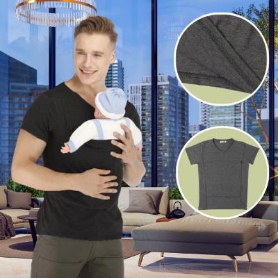 bébé-installé-face-a-son-papa-dans-un-porte-bébé-physiologique-T-shirt-noir-dans-le-salon-d-un-appartement-avec-vue-sur-les-immeubles