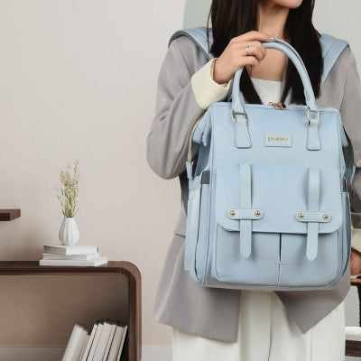 Maman-dans-son-salon-portant-son-sac-à-dos-à-langer-bleu-contemporain-design-doté-de-poches-spacieuses-et-élégantes-avec-des-poignées-renforcées