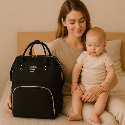 Bebe assis lit maman regardant sac a langer de luxe design noir sangles ajustables