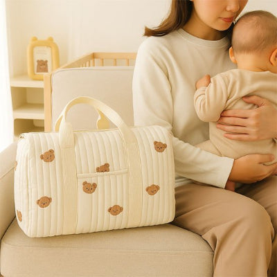Bébé assis genoux maman devant sac bebe à langer design élégant beige sac à main chambre