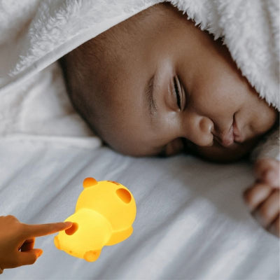 Bébé-dormant-dans-son-lit-chaleureusement-emmitouflé-dans-une-couverture-blanche-dont-le-visage-est-éclairé-par-sa-veilleuse-bébé-jaune-rassurante.