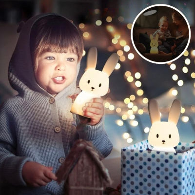 Petit-enfant-dans-sa-chambre-tenant-entre-ses-mains-sa-veilleuse-bébé-en-forme-de-lapin-en-mode-lumière-douce-et-chaude-illuminant-son-visage
