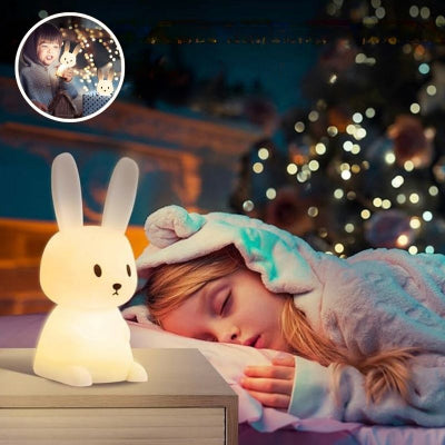 Jeune-enfant-dormant-paisiblement-dans-son-lit-à-côté-duquel-est-posée-sa-veilleuse-bébé-en-forme-de-lapin-sur-sa-table-de-nuit-rayonnante-et-la-rassurant